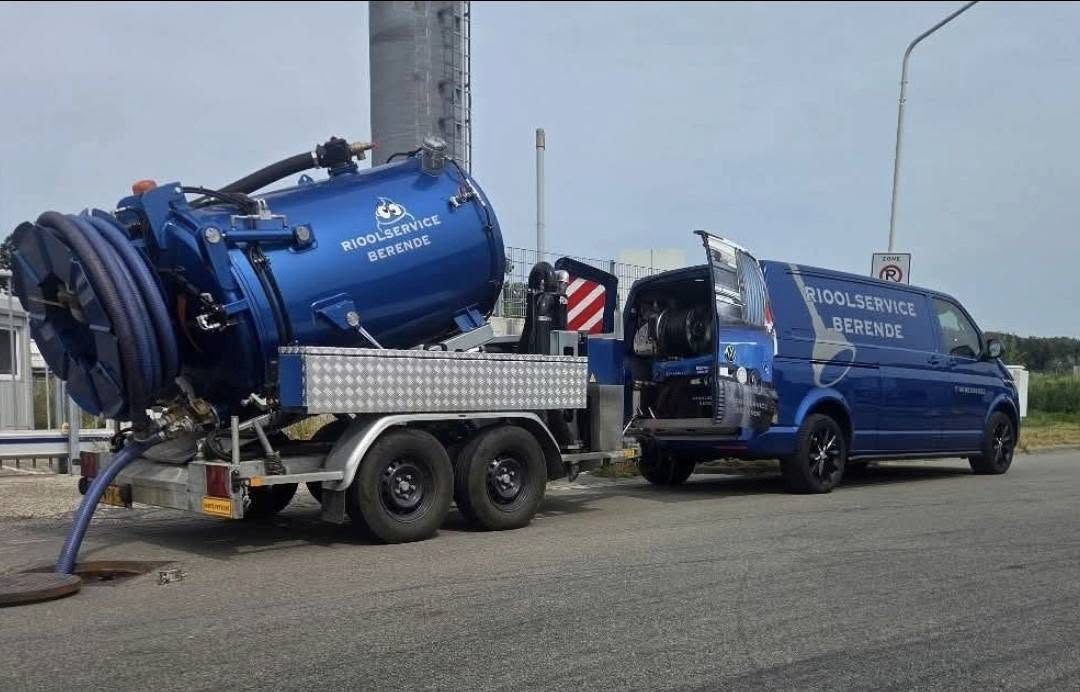 De blauwe bus van Rioolservice Berende met de zuigaanhanger, klaar bij een put langs de weg